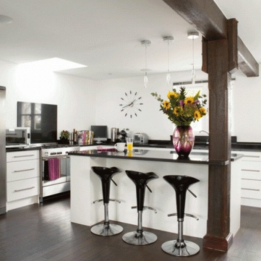 Bar berdiri-pulau di interior dapur hitam dan putih secara harmonis dikombinasikan dengan dukungan kayu untuk balok langit-langit
